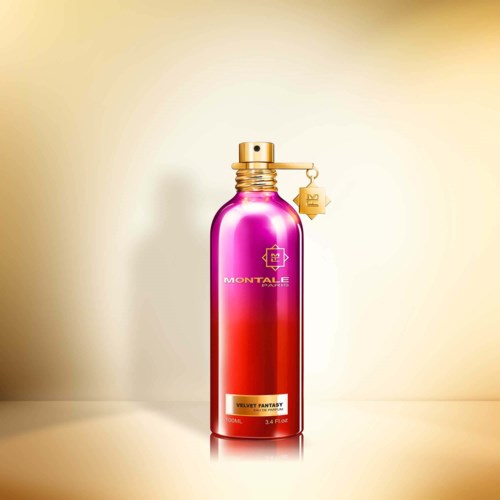 Eine lange, glänzende, rosa und goldene Flasche mit Schraubverschluss und kleinem Anhänger. Es steht "Velvet Fantasy" auf dem Etikett.