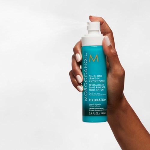 Käsien pitää turkoosipäällystettä, jossa lukee 'Moocanoil' ja spraykorkki.