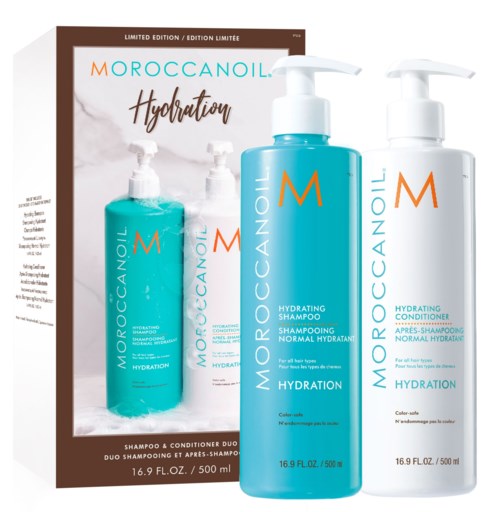 Två flaskor Moroccanoil återfuktande schampo och balsam, med ett relaterat produktblad bakom dem.