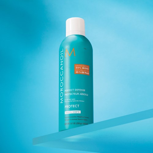 A blue bottle with a white cap holds Moroccanoil Protect spray, featuring a label and orange sticker on a blue background.