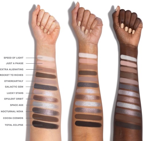 Three arms with different skin tones show swatches of various eyeshadow shades, from light to dark, in a vertical line.