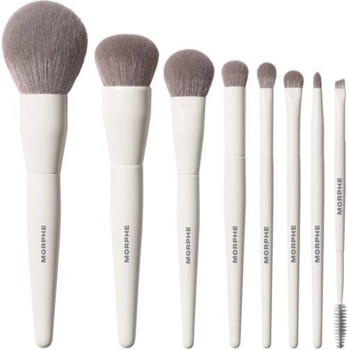 Sæt med otte hvide makeupbørster med grå spidser, arrangeret efter størrelse fra størst til mindst.