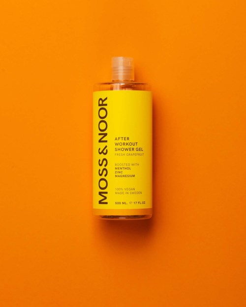 Gul flaske af Moss & Noors efter træning shower gel med grapefruit duft på orange baggrund.