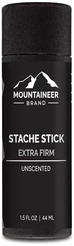 En svart pinne med fjelllogo, merket 'Mountaineer Brand Stache Stick Extra Firm Unscented, 44 ml.'