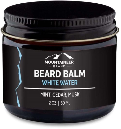 A black container with a label, showing Mountaineer Beard Balm, White Water scent, 2 oz size, ingredients include mint, cedar, musk.