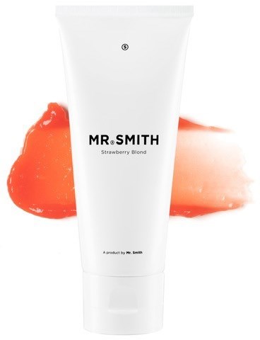En hvit tube med Mr. Smith-produkt med jordbærblond duft, foran oransjefargede flekker.
