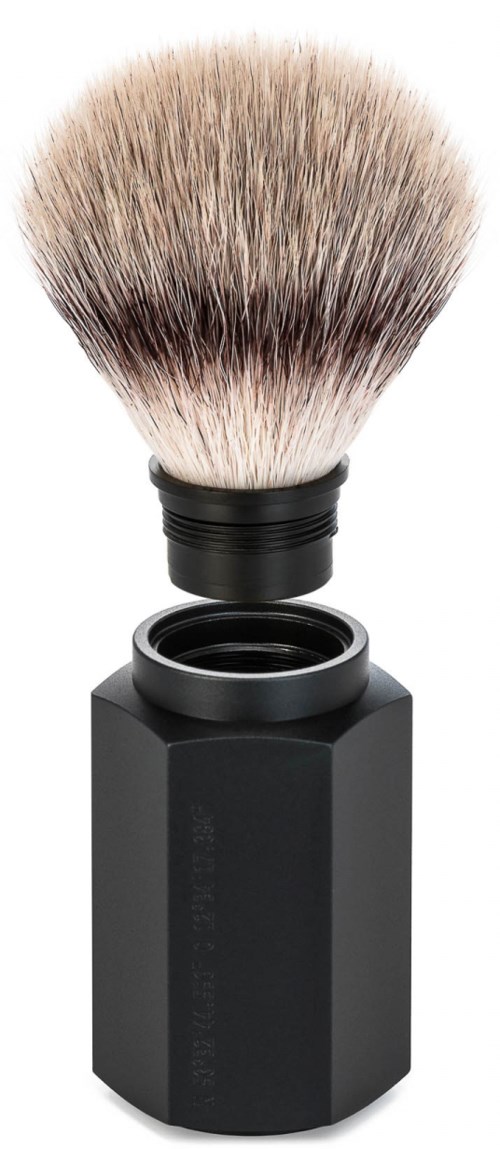 En barberkost med sort skaft og bløde, fluffy børster, placeret over en sort beholder.