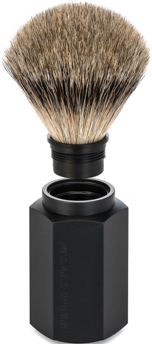 En barberkost med svart håndtak og myke børster på toppen, ved siden av en svart flaske eller beholder.