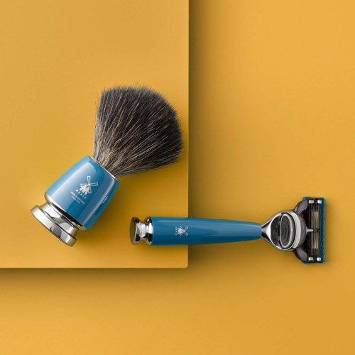 En barberkost og barberblad med blå håndtag på gul baggrund.
