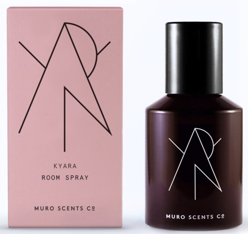 En rosa eske og en mørk flaske med enkel svart-hvitt geometrisk linjekunst. Esken sier Kyara Room Spray.