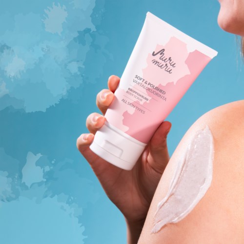 A person holds a pink tube of body lotion near their shoulder with some cream applied on the skin.