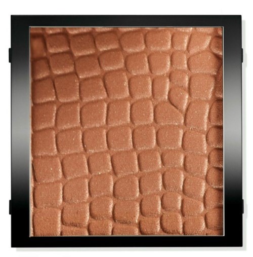En närbild av brunt makeuppulver med ett texturerat krokodilmönster i en svart kompakt.