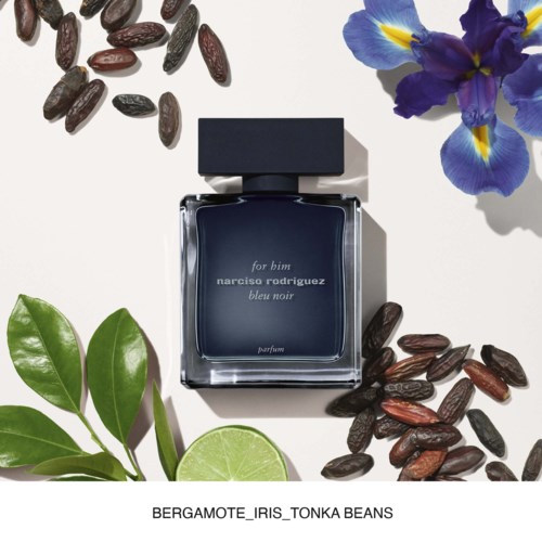 Ciemnoniebieska butelka perfum z napisem 'for him narciso rodriguez bleu noir', otoczona irysami, fasolami, liśćmi i limonką.