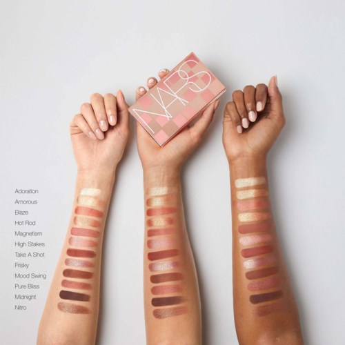 Two hands show swatches of various makeup shades, with a NARS makeup box above. The shades range from light to dark.