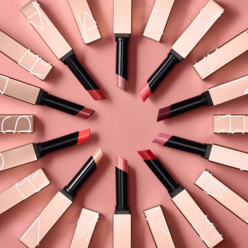 Lipstick tubes arranged in a circle with various shades on a pink background.