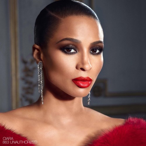 A woman with dark hair, bold makeup, red lipstick, diamond earrings, and a red fur outfit.
