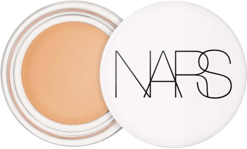 En liten behållare med beige makeup och vit lock med NARS-logga.