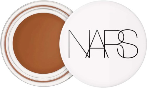 Ett brunt kosmetiskt produkt i en rund behållare med lock som är vit och har svarta linjer och NARS skrivet på.