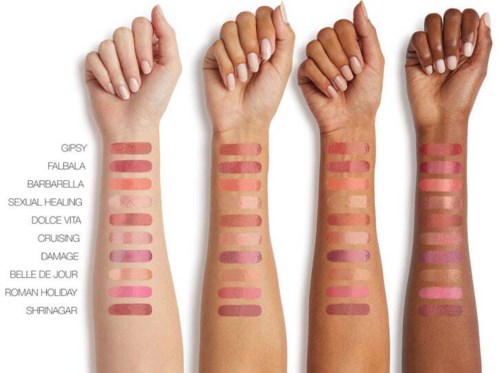 Fyra armar med hudfärgsstavar som är märkta med olika namn, visar olika nyanser av läppstift eller makeup. Armarna går från ljus till mörk hudton.