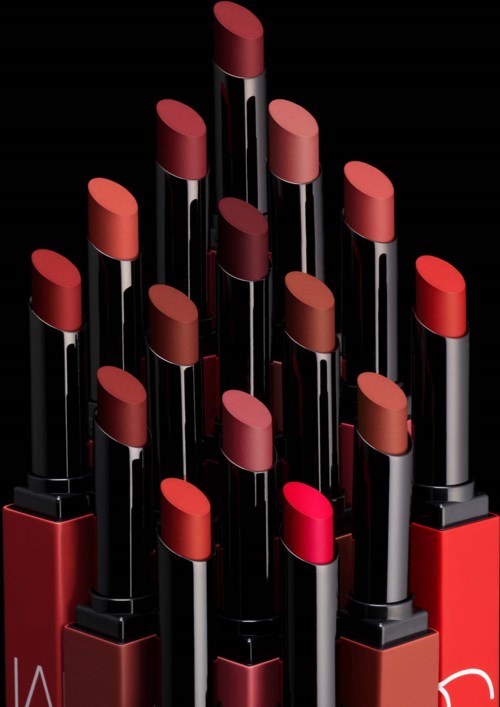 Several lipsticks in various shades arranged in a pyramid shape on a black background.
