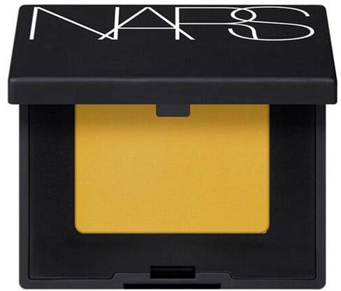 En NARS make-up dosa med gul puder inuti och ett svart skal med vitt märke på toppen.
