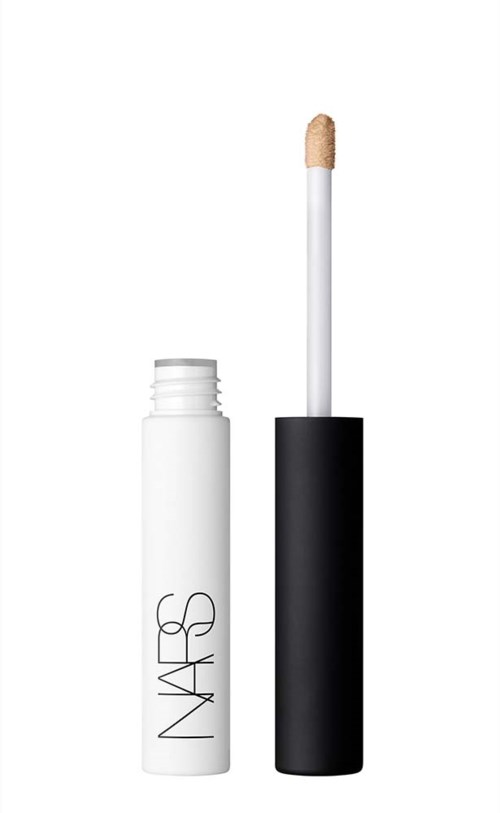 Valkoinen putki ja musta korkki, ja sisällä on harja, jossa on beige päitä.