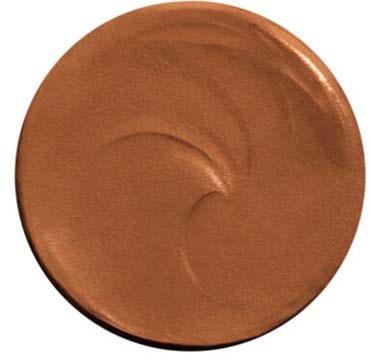 Et rundt sminkeprodukt, muligens foundation eller blush, med glatt, blank overflate og et lite sirkulært mønster.