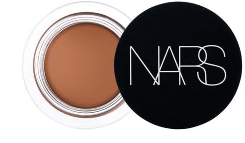 Ein NARS-Grundierungsglas mit dem Deckel daneben, zeigt die beige Flüssigkeit.