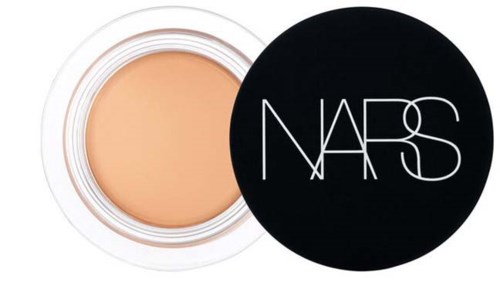 En rund åben beholder med beige makeup og sort låg med NARS-logo.