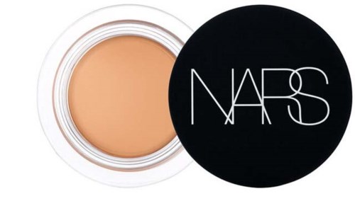 Ein runder Behälter mit beige Make-up und einem schwarzen Deckel mit weißen NARS-Logo.