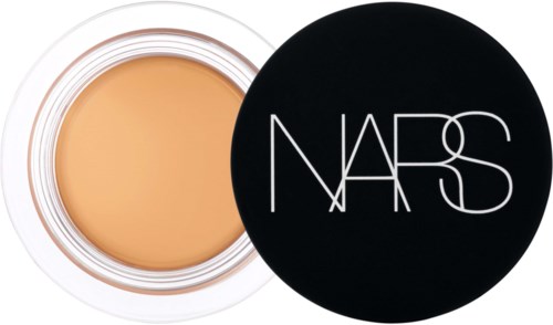 Ein runder Behälter mit beige Make-up und schwarzem Deckel mit weißem NARS-Logo.