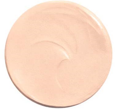 En rund, ljusbeige makeup- eller hudvårdsgrädde i behållare, slät och något glansig på ytan.