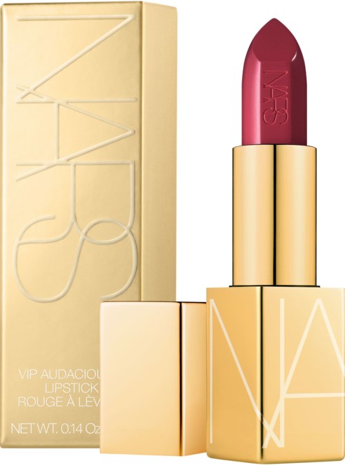 A NARS lipstick with a gold case and pink lipstick inside, standing next to its beige box.