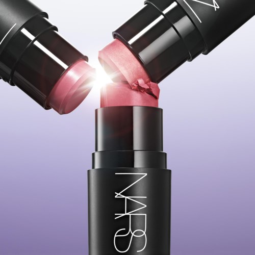 Two lipsticks are breaking, with pink lipstick spilling out. The lipsticks are held above a black NARS container.