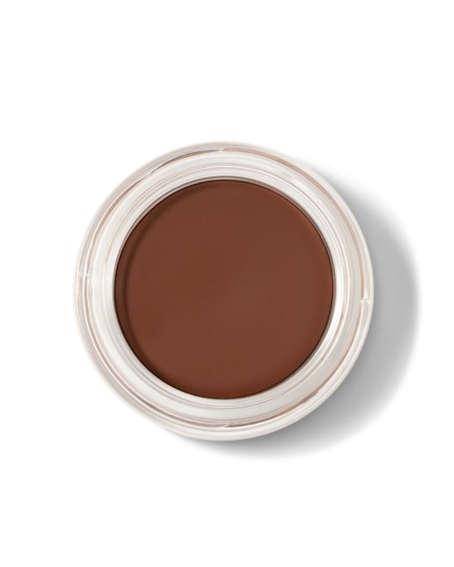Brunt makeupprodukt i en lille rund beholder set ovenfra. Ingen etiketter synlige.