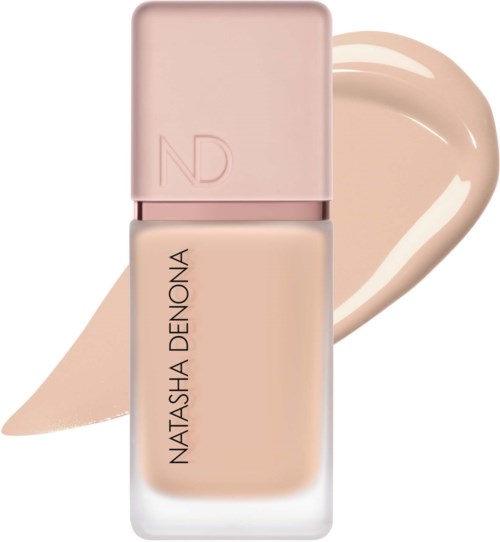 En flaska beige flytande foundation med rosa lock och ett streck av produkten bakom den.