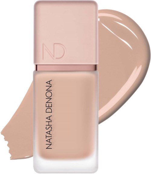 En flaska foundation i ljus beige färg med ett rosa lock, som heter Natasha Denona.