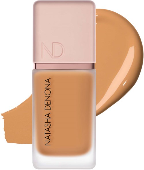 En flaska av Natasha Denona foundation med ett ljust rosa lock och en test av foundationfärgen