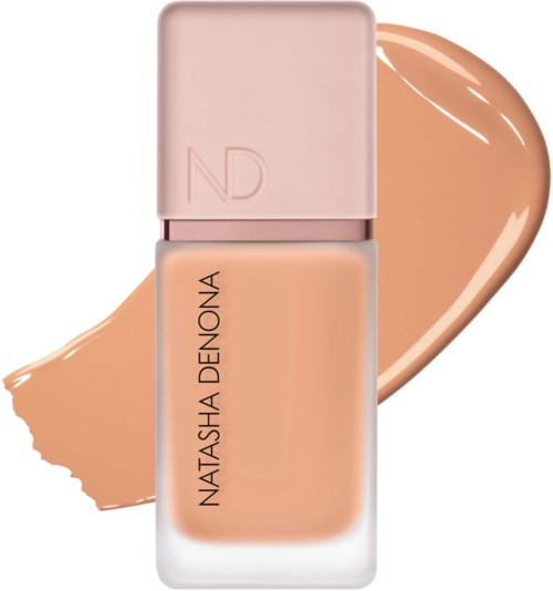 En foundationflaska med rosa lock och märket Natasha Denona, med en skugga av beige foundation bakom.