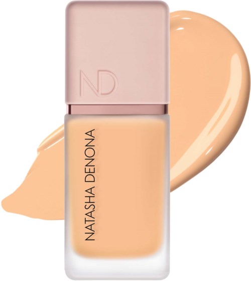 En foundationsflaska från Natasha Denona med ett rosa lock och beige flytande foundation inuti.