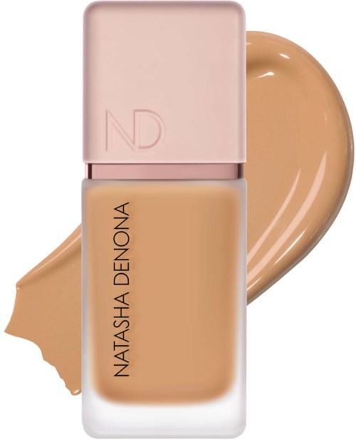 En flaska foundation med rosa lock och ett swatch av beiget smink bakom.