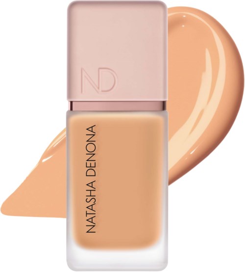 En beige flytande foundationflaska med rosa lock och en liten mängd av produkten bakom.