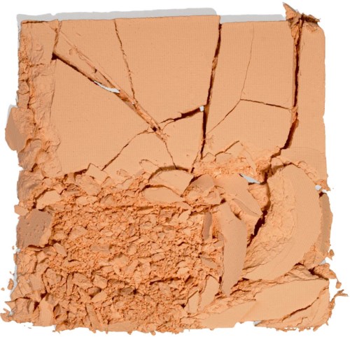 Sprucken beige ansiktspuder med puder spritt runt och några stora bitar.