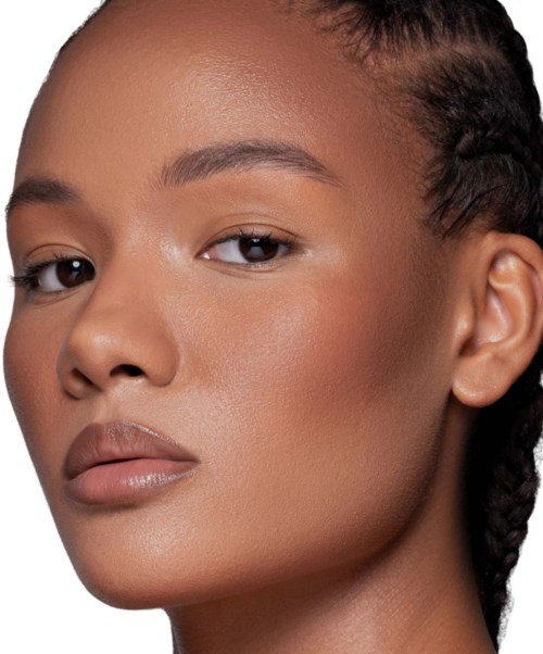 En ung kvinna med välskött hår och naturlig makeup tittar självsäkert på kameran.