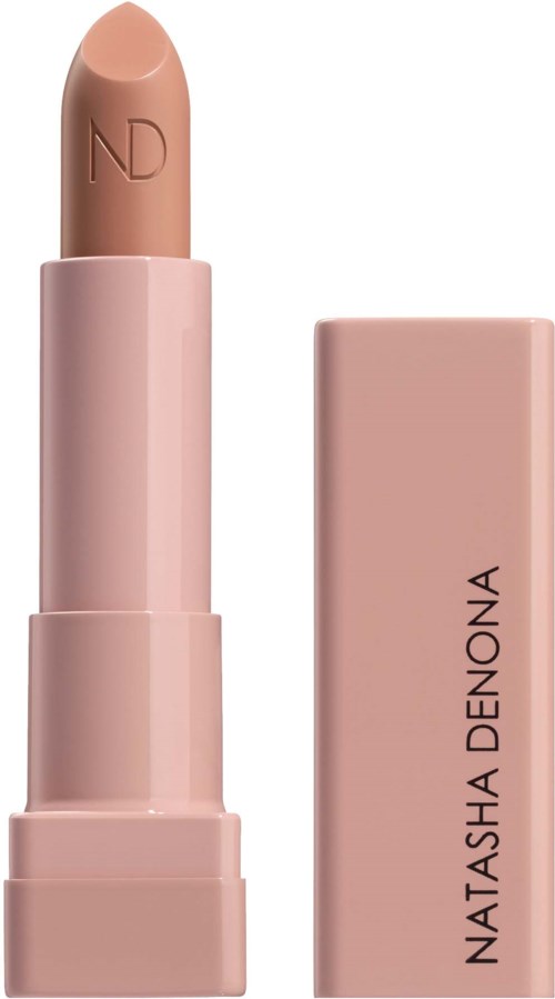 Ein nude Lippenstift in rosa Verpackung, der Stift ist leicht herausgedreht, zeigt die weiche beige Farbe. Die Verpackung trägt den Namen Natasha Denona.