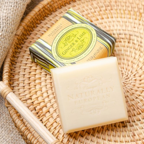 En tvålarpår märkt 'Naturally European' och en liten box märkt 'Ginger & Lime' på en vävt korg.