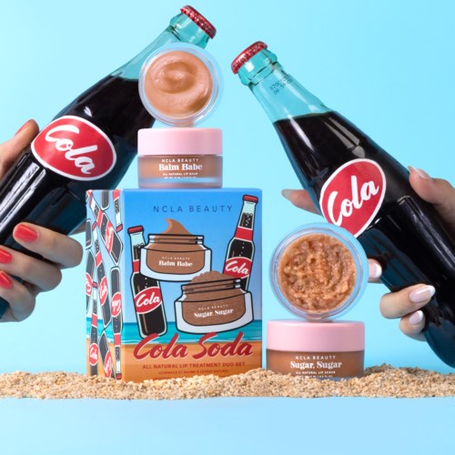 Kaksi kättä pitää lasipulloja, joissa lukee 'Cola'. Taustalla värikäs laatikko ja purkkeja.