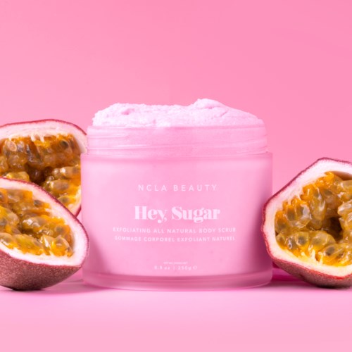 Vaaleanpunainen purkki merkitty 'Hey, Sugar' passionhedelmän puolikkaiden ympäröimänä vaaleanpunaisella taustalla.