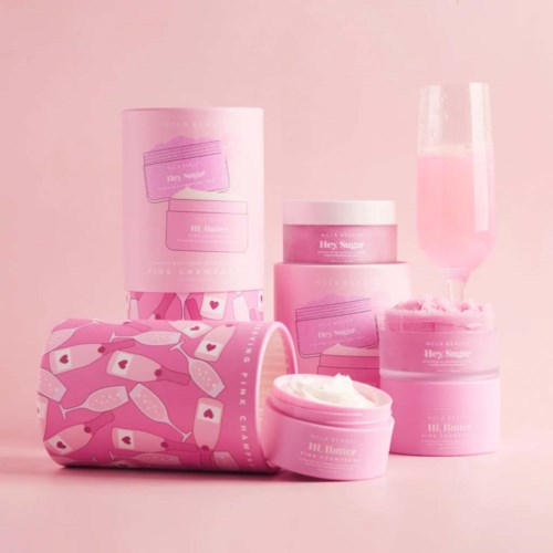 Skönhetsprodukter och ett rosa glas sprayade i en rosa bakgrund.