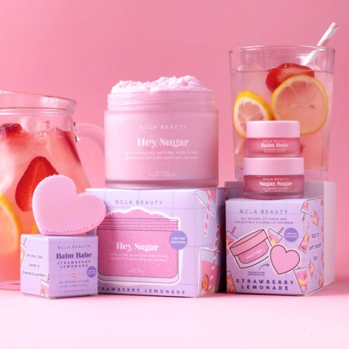 Beauty products and drink with strawberries and lemon slices on pink background.